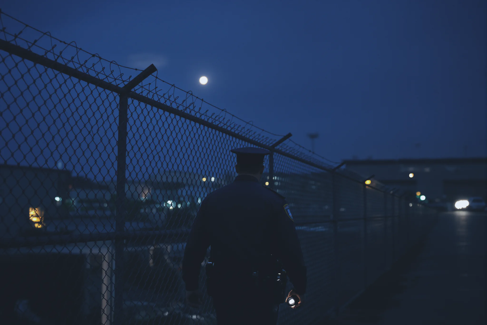 A Sentinel responder walking an industrial fence line at night.